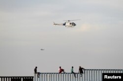 Migrants, part of a caravan of thousands trying to reach the U.S., sit on top of the border fence between Mexico and the United States, after arriving in Tijuana, Mexico, Nov. 13, 2018.