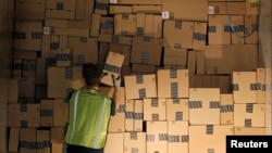 Un trabajador apila un remolque de envío con artículos en cajas para entregar en el centro de distribución de Amazon en Phoenix, Arizona.