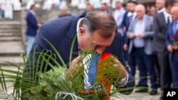 Milorad Dodik ljubi zastavu entiteta na vojničkom groblju u Bratuncu, u okolini Srebrenice, na dan donošenja rezolucije UN-a kojom se 11. juli proglašava međunarodnim danom sjećanja na genocid u Srebrenici.