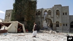 A man loyal to former Yemeni president Ali Abdullah Saleh stands guard at Saleh's house destroyed by a Saudi-led airstrike in Sanaa, Yemen, Sunday, May 10, 2015.