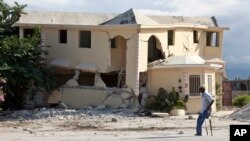FILE - A man walks on crutches past a building destroyed by the earthquake in Leogane, Haiti, Dec. 12, 2010.