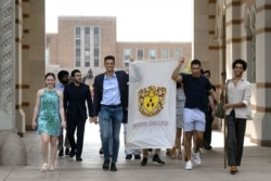 In this March 13, 2020 photo, seniors at Rice University parade through the school's main archway, known as the Sallyport, to continue a commencement tradition at the school in Houston.