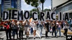 Anti-government demonstrators hold a poster that reads in Spanish "Democracy" during a protest against Venezuela's President Nicolas Maduro in Caracas, Venezuela, Aug. 12, 2017.