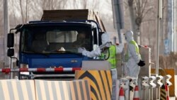 身穿防護服的警察在河北省合格北京的一個道路檢查站攔住卡車卡車。（2021年1月12日）