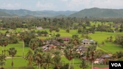 ភូមិមួយក្នុងខេត្តកំពតដែលរុំព័ទ្ធដោយវាលស្រែបៃតងខ្ចីក្នុងរដូវវស្សា នៅថ្ងៃទី៤ ខែតុលា ឆ្នាំ២០១៤។ (នូវ ពៅលក្ខិណា VOA)