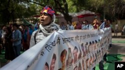 រូបភាព​ឯកសារ៖ ជនជាតិ​ទីបេ​ម្នាក់​ច្រៀង​ចម្រៀង​ជាតិ​ខណ​ដែល​លោក​កាន់​ស្លាក​ជាមួយ​អ្នក​ផ្សេង​ទៀត​បង្ហាញ​ពីជន​ដុត​សម្លាប់​ខ្លួន​ឯងអំឡុង​បាតុកម្ម​មួយ​ក្នុង​ទីក្រុ​ង​ញុវ​ដែលី​កាលពី​ថ្ងៃទី​២៥ មេសា ២០១៤។