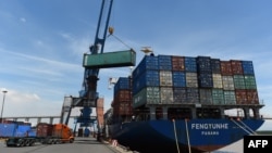 FILE - Containers are transferred from a truck to a cargo ship at the international cargo terminal of a port in Hai Phong, Vietnam, Aug. 12, 2019.