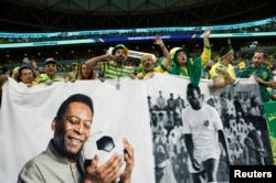 Mashabiki wa Brazil wakionyesha mabango ya picha ya mchezaji wa zamani wa Brazil Pele ndani ya Uwanja wa Mpira wakati wa Mashindano ya Kombe la Dunia ya FIFA Qatar 2022. REUTERS/Benoit Tessier