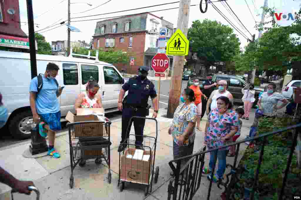 El oficial Fernando Badillo y su compañero de turno ayudan a los vecinos a descargar de la camioneta las pesadas cajas de alimentos.