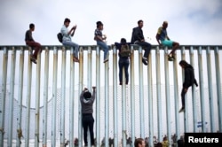 Members of a caravan of migrants from Central America climb up the border fence between Mexico and the U.S., as a part of a demonstration prior to preparations for an asylum request in the U.S., in Tijuana, Mexico April 29, 2018.