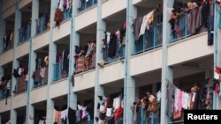 Palestinci, koji su napustili svoje domove zbog izraelskih napada, gledaju obližnji izraelski napad dok se sklanjaju u školu koju vode UN, u Khan Younisu