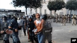 La police anti-émeute libanaise arrête un manifestant anti-gouvernemental, qui tentait d'atteindre le bâtiment du Parlement, lors d'une manifestation contre les élites politiques et le gouvernement, à Beyrouth, au Liban, le samedi 8 août 2020. (Photo AP / Hussein Malla)