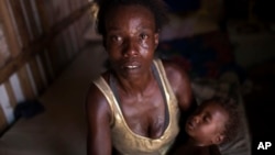 In this Oct. 20, 2017 photo, Simone Batista, holding her baby Arthur, looks into the camera as tears roll down her cheeks while she recounts being cut from the "Bolsa Familia" government subsidy program for low-income people, at her shack home in the Jardim Gramacho slum of Rio de Janeiro, Brazil. (AP Photo/Silvia Izquierdo)
