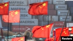 Кинеските национални знамиња се веат во близина на бродските контејнери во пристаниште надвор од Шангај, 7 февруари 2025 година