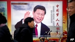 资料照片：北京街头人们走过一个有着习近平肖像，并写着“中国梦，人民的梦”的广告看板。（2018年3月2日）