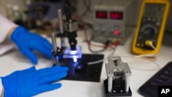 A SpacePharma employee works beside a miniature laboratory that will carry out experiments in space, in their offices in Herzliya near Tel Aviv Feb. 24, 2015.