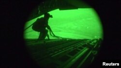 FILE - Still from night-vision footage shows Air Force personnel retrieving straps after U.S. military airdrop of food and water for thousands of Iraqi citizens threatened by Islamic State militants in 2014.