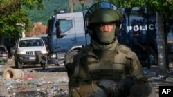 Soldados de la KFOR, la fuerza de paz de la OTAN, y policías de Kosovo protegen un edificio municipal tras los choques entre personas de etnia serbia y tropas de KFOR, en Zvecan, Kosovo, el martes 30 de mayo de 2023. 