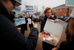La candidata a la nominación presidencialo demócrata Elizabeth Warren ofrece donas a partidarios en un puesto de votación en Portsmouth, New Hampshire, el martes, 11 de febrero de 2020.