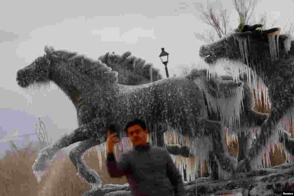 A man takes a selfie at the "Los Indomables" monument with frozen water during a day of low temperatures, in Ciudad Juarez, Mexico, Jan. 8, 2025. 