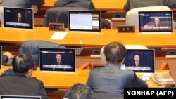 Legisladores surcoreanos miran pantallas que muestran una transmisión del discurso del presidente Yoon Suk Yeol sobre el levantamiento de la ley marcial, en la Asamblea Nacional en Seúl, el 4 de diciembre de 2024.
