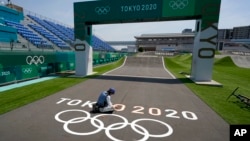 A worker paints Olympic rings at the finish line of the BMX racing track as preparations continue for the 2020 Summer Olympics, Tuesday, July 20, 2021, at the Ariake Urban Sports Park in Tokyo. (AP Photo/Charlie Riedel)