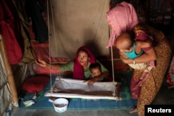 Rohingya refugee women arrange a cradle for child in their makeshift tent in the Balukhali refugee camp in Cox's Bazar, Bangladesh, Aug. 23, 2018.