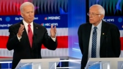 Otro momento del debate. El ex vicepresidente Joe Biden (izq) habla mientras el senador Bernie Sanders (der) escucha.