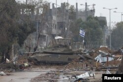Bendera Israel berkibar di atas tank, sementara warga Palestina yang melarikan diri dari Gaza utara bergerak ke selatan selama gencatan senjata sementara antara Israel dan Hamas, dekat Kota Gaza 27 November 2023. (Foto: REUTERS/Ibraheem Abu Mustafa)