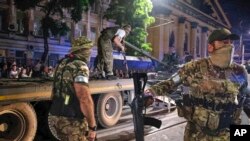 Anggota perusahaan militer Grup Wagner menjaga suatu daerah saat yang lain memuat tank mereka ke truk di sebuah jalan di Rostov-on-Don, Rusia, Sabtu, 24 Juni 2023. (Vasily Deryugin, Rumah Penerbitan Kommersant via AP)