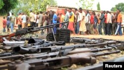 Suspected fighters are paraded before the media by Burundian police near a recovered cache of weapons after clashes in the capital Bujumbura, Burundi, Dec. 12, 2015.