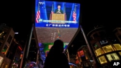 រូបឯកសារ៖ ស្ត្រី​ម្នាក់ ឈរ​នៅក្បែរ​កញ្ចក់​ទូរទស្សន៍​ដ៏ធំ​មួយ​នៅ​ផ្សារទំនើប​មួយ​កន្លែង​នៅ​ក្នុង​ទីក្រុង​ប៉េកាំង ដែល​ផ្សាយ​ព័ត៌មាន​នៅពេល​ដែល​លោក Joe Biden ដែល​​នៅ​ពេល​នោះ លោក​ជាប្រធានាធិបតី​ជាប់ឆ្នោត​សហរដ្ឋ​អាមេរិក បាន​ថ្លែងសុន្ទរកថា នៅ​ថ្ងៃទី៨ ខែវិច្ឆិកា ឆ្នាំ២០២០។