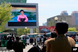 North Koreans watch as their country's most famous newscaster announces leader Kim Jong Un's proposal to suspend nuclear tests and long-range missile launches on a giant screen on Pyongyang's newly built Mirae Scientists' Street.