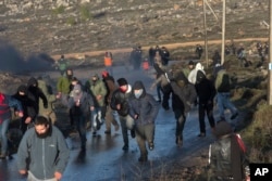 Jewish settlers run from police outside the Amona outpost in the West Bank, Feb. 1, 2017. The military issued eviction orders the day before, telling residents to evacuate Amona within 48 hours and blocked roads leading to the outpost.