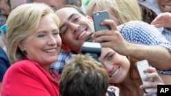 Democratic presidential candidate Hillary Rodham Clinton poses for a photo with two of her supporters on the campus of Case Western Reserve University in Cleveland.