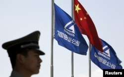 FILE - A security guard stands in position in front of the company's and Chinese flags outside the headquarters of Aluminum Corp of China (Chinalco) in Beijing in this June 5, 2009 file photo.