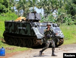 A government troop gestures as he passes an armoured personnel carrier posted along a main highway of Pantar town, Lanao Del Norte, after residents start to evacuate their hometown of Marawi city, southern Philippines, May 24, 2017.