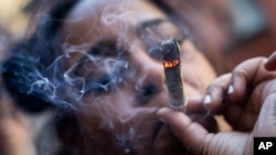 FILE - A person smokes cannabis outside the Smacked "pop up" cannabis dispensary location, Tuesday, Jan. 24, 2023, in New York. (AP Photo/John Minchillo)