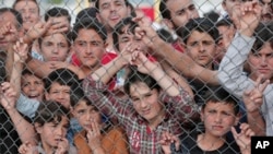 Migrants stand behind a fence at the Nizip refugee camp in Gaziantep province, southeastern Turkey, April 23, 2016. 