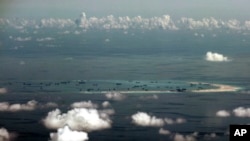 FILE - In this Monday, May 11, 2015, file photo, This aerial photo taken through a glass window of a military plane shows China's alleged on-going reclamation of Mischief Reef in the Spratly Islands in the South China Sea. The dispute over the…