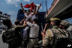 Indian policemen detain Kashmiri Shiite Muslims for participating in a religious procession during restrictions in Srinagar, Indian controlled Kashmir, Sunday, Aug. 7, 2022. Authorities had imposed restrictions in parts of Srinagar, the region's main city, to prevent gatherings marking Muharram from developing into anti-India protests. (AP Photo/Mukhtar Khan)