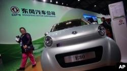 A visitor looks at an E30 EV, a small electric vehicle of Chinese state-owned automobile manufacturer Dongfeng Motor Co., at China International Industry Fair in Shanghai, Nov. 5, 2013. 