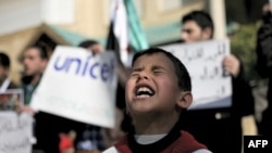 اردن ٢٠١٢ کال، د سوریې یو کډوال ماشوم د جگړې د ختمولو په لاریون کې پر ملگرو ملتونو د مرستې غږ کوي. 