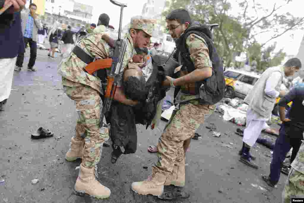 Shi'ite Houthi rebels carry a dead man at the scene of a suicide attack in Sana'a, Oct. 9, 2014. 