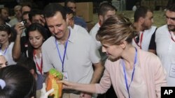 Suriya rahbari Bashar al-Assad va uning rafiqasi Asma poytaxt Damashqda Hims ahli uchun insonparvarlik yordamini taxlamoqda, 16-aprel, 2012-yil
