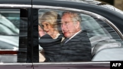 Britain's King Charles III and Britain's Queen Camilla wave as they leave by car from Clarence House, traveling to Buckingham Palace, in London on February 6, 2024. (Photo by HENRY NICHOLLS / AFP)
