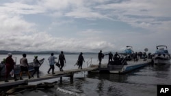 Migrantes abordan un barco hacia el Tapón del Darién, en Necoclí, Colombia, el 7 de octubre de 2023.