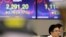 A currency trader watches the computer monitors near the screens showing the Korea Composite Stock Price Index (KOSPI), left, and the foreign exchange rate between U.S. dollar and South Korean won at the foreign exchange dealing room in Seoul, South Korea