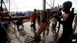 Migrant workers unload frozen fish from a boat at a fish market in Samut Sakhon Province, west of Bangkok, Thailand, June 20, 2014. 