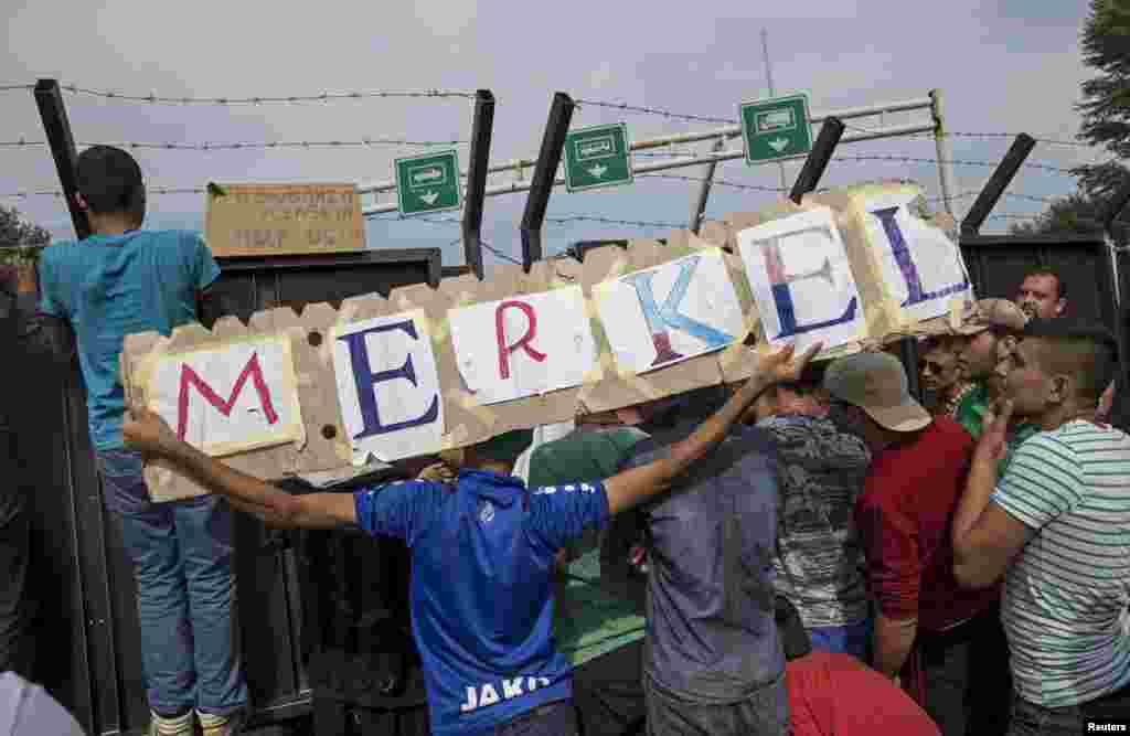 Migrants hold a banner reading "Merkel" in front of a barrier at the border with Hungary near the village of Horgos, Serbia.